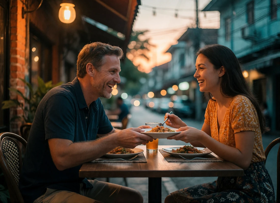 Thai woman passing a dish to a Western man across a small outdoor table at a street food stall in the evening